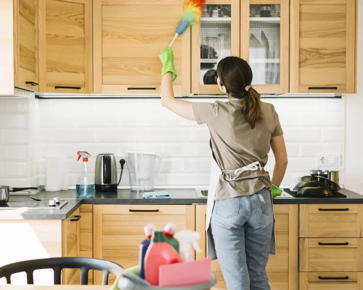 Mulher usando espanador para limpeza da casa