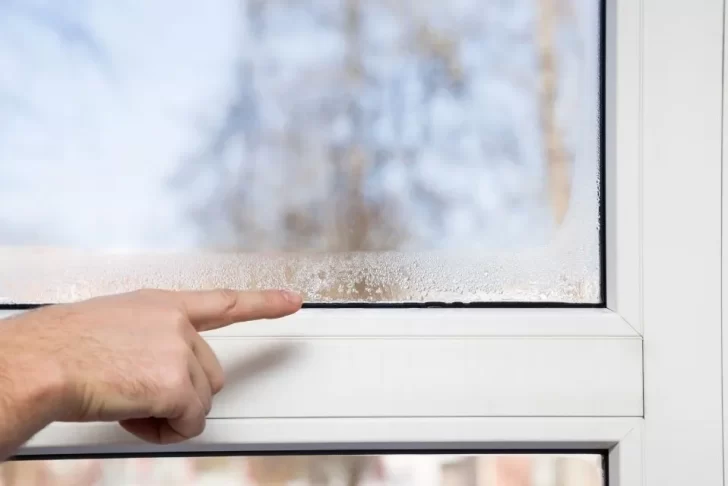 homem aponta para janela com sinais de umidade