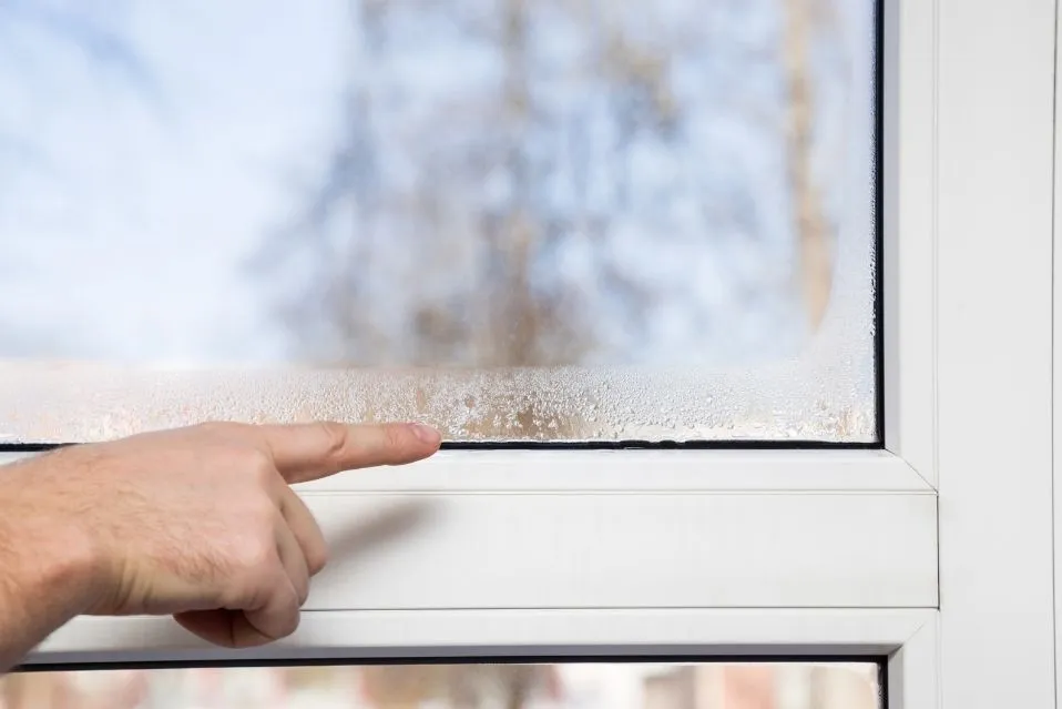 homem aponta para janela com sinais de umidade