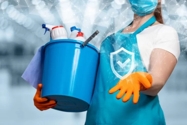 mulher faz limpeza com balde e equipamento de proteção individual